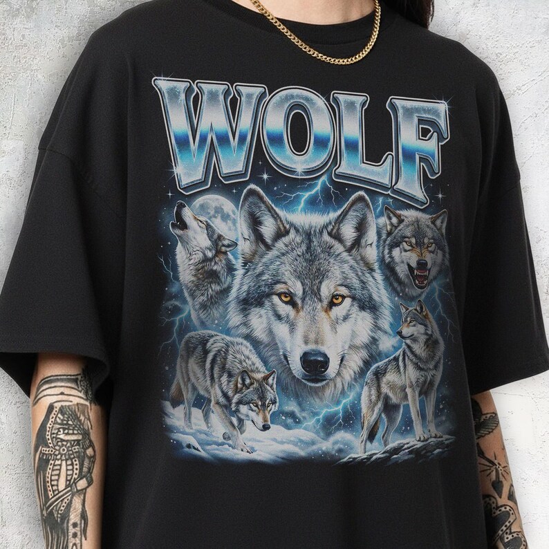 Model wearing a vintage wash black t-shirt featuring a collage of wolves howling at the moon with icy blue lightning, large metallic text reading WOLF in 90s bootleg style.
