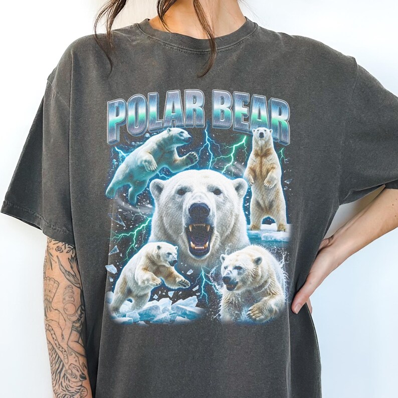 May include: Dark gray t-shirt featuring a graphic of polar bears with the text "POLAR BEAR" in a blue and silver font. The design includes multiple polar bears in various poses, with lightning bolts in the background.