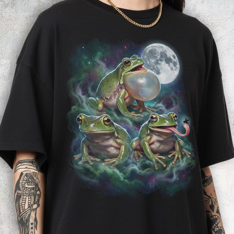 Three realistic green frogs positioned under a large luminous full moon. The top frog has an inflated translucent vocal sac as if croaking. Below, one frog faces forward with a calm expression, while the other sticks its long tongue out to catch a fly. Cosmic teal and purple nebula mist with stars in a retro 90s galaxy style.