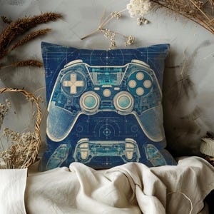 May include: A square throw pillow featuring a dark blue blueprint design of a video game controller. The graphic displays technical schematic lines, crosshairs, and a detailed outline of the controller in a light cyan and white colour palette.