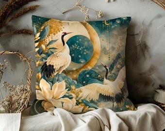 May include: Square decorative pillow with a crane design. The pillow features a teal and gold color scheme with a celestial theme, including a moon and stars. The cranes are depicted with white, black, and red details, surrounded by floral elements.
