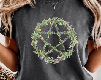 May include: Dark gray t-shirt featuring a floral pentagram design. The pentagram is composed of green leaves, yellow and purple flowers. The shirt is a crew neck style.