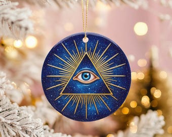 May include: A round, blue Christmas ornament with a gold string for hanging. The ornament features a gold triangle with an eye in the center, surrounded by gold rays against a starry background.