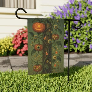 May include: A Halloween garden flag featuring a spooky tree with pumpkins, eyeballs, skulls, and candy corn. The flag is displayed on a black metal stand in a grassy yard, with flowers and a house in the background.