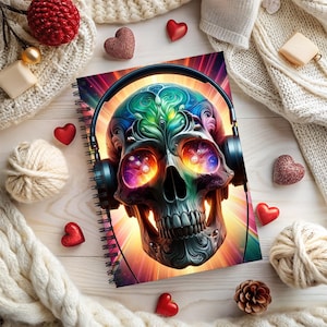 May include: Spiral-bound notebook featuring a vibrant, colorful skull design wearing headphones. The skull's eyes glow with a cosmic pattern, and the background radiates with warm hues. The notebook is surrounded by decorative elements.