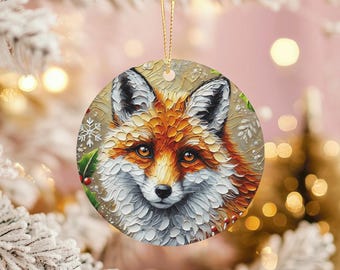 Peut inclure: Ornement de Noël rond avec une illustration détaillée d'un visage de renard. Le renard a une fourrure orange et blanche, avec des accents noirs sur les oreilles et le nez. Le houx et les flocons de neige décorent les bords. Une ficelle dorée est attachée pour l'accrocher.
