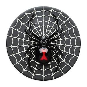 May include: A black spider with a red hourglass marking is centered on a black coaster with a white spiderweb design. The spider has eight legs and is glossy. The coaster is round and has a matte finish.