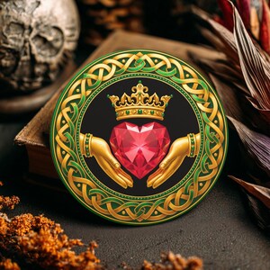 May include: Round Claddagh design coaster with a black background, featuring a red heart, gold crown, and hands. The design is framed by a green and gold Celtic knot border. The coaster is likely made of ceramic or a similar material.