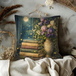 May include: Decorative square pillow featuring a stack of books, a vase of purple and white flowers, and a moonlit scene. The pillow has a vintage, artistic design with a soft, muted color palette. The books are stacked in front of the vase.