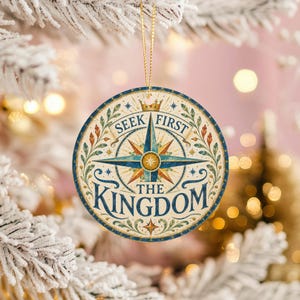 Peut inclure: Une décoration de Noël ronde et plate ornée d'une rose des vents centrale bleue et dorée. Le texte SEEK FIRST THE KINGDOM est imprimé en lettres bleu foncé. L'ornement est décoré de feuillages verts et orange et d'une petite couronne dorée.