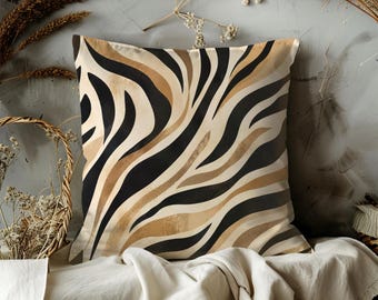 May include: Square decorative pillow with a zebra stripe pattern in black, tan, and brown. The pillow is placed on a white surface with dried plants and a basket in the background. The pillow has a neutral color palette.