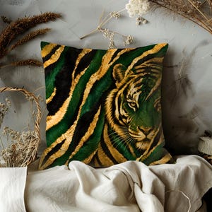 May include: Square decorative pillow featuring a tiger face and striped pattern in shades of green, black, and gold. The pillow is placed on a white surface, with dried plants and a basket in the background.