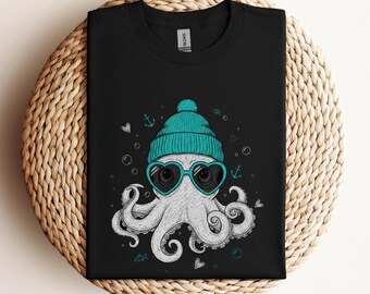 May include: Black t-shirt featuring a white octopus wearing a teal beanie and heart-shaped sunglasses. The octopus design includes teal accents of anchors, bubbles, and hearts. The shirt is displayed on a woven surface.