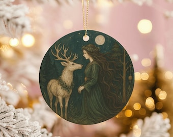 May include: Round Christmas ornament featuring a forest scene with a woman in a green dress and a deer. The woman has long brown hair and a wreath. The deer has large antlers and a wreath. The background is a dark blue with a full moon.