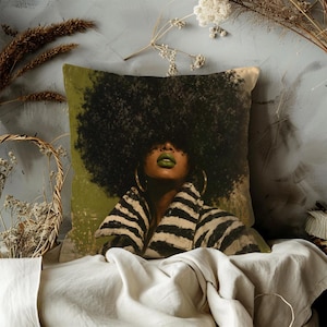May include: Square decorative pillow featuring a portrait of a person with a large afro, green lipstick, and gold hoop earrings. The person is wearing a black and white striped jacket. The background has a green and beige color scheme.