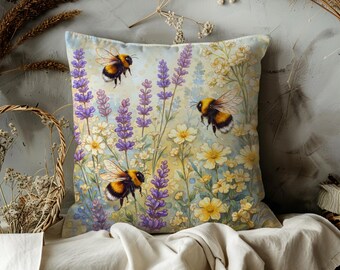 May include: Square decorative pillow featuring a watercolor design of bumblebees, lavender, and wildflowers. The pillow has a light blue background with yellow, purple, and white floral elements. The bees are black and yellow.