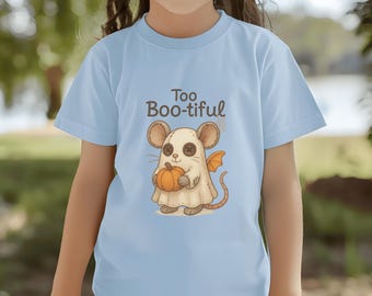 May include: Light blue t-shirt featuring a cartoon mouse dressed as a ghost, holding a pumpkin. The mouse has large ears and a long tail. The text "Too Boo-tiful" is above the mouse. A fun Halloween-themed design.