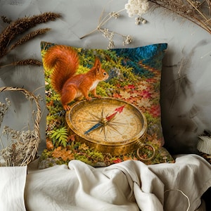 May include: A square throw pillow featuring a vibrant printed scene of a red squirrel standing on a large, antique-style brass compass. The background depicts a lush forest floor covered in colourful autumn leaves, green ferns, and mossy textures.