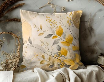 May include: Square decorative pillow with a botanical design. The pillow features a cream-colored background with yellow and gray leaves and floral accents. The design has a watercolor style with a soft, natural aesthetic.