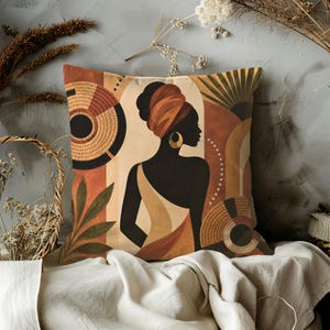 Può includere: Un cuscino quadrato con un'illustrazione grafica di una persona con un foulard e un grande orecchino a cerchio. Il design include forme geometriche astratte, motivi circolari intrecciati e foglie nei toni del terracotta, beige e nero.