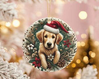 Puede incluir: Adorno navideño redondo con un golden retriever con gorro de Papá Noel. El perro está rodeado por una corona de vegetación, flores blancas, poinsettias rojas y piñas. Una cuerda dorada está unida para colgar.