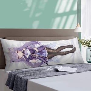 Może przedstawiać: Długa, prostokątna poduszka do ciała z fioletowowłosą postacią z anime w fioletowym i białym stroju. Postać leży na białym tle. Poduszka leży na ł&oacute;żku z szarym kocem.