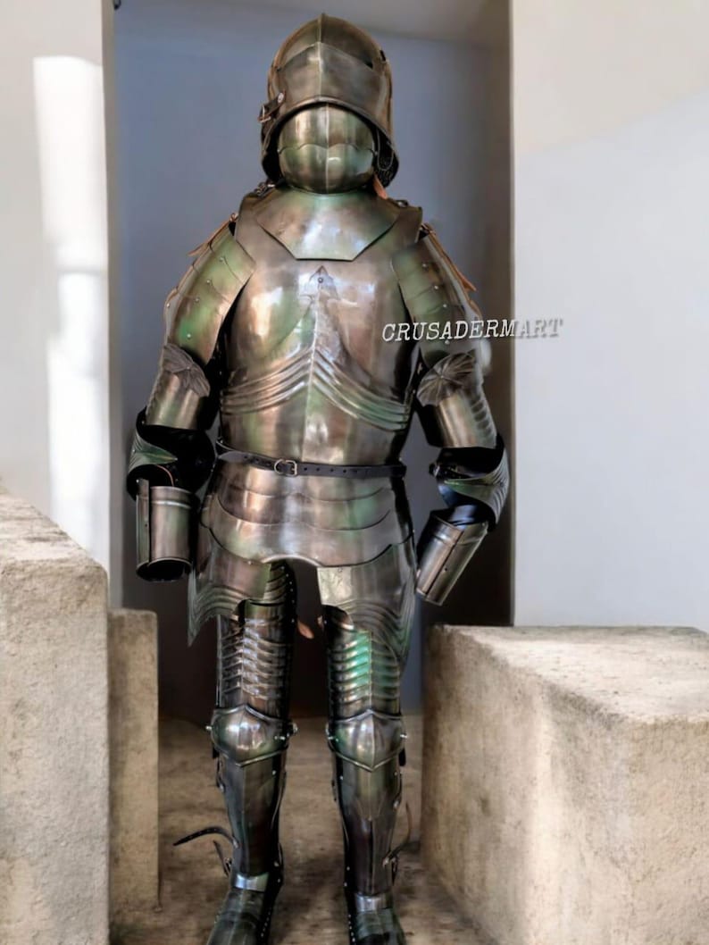 May include: Full suit of medieval armor, featuring a helmet, chest plate, and leg guards. The armor is made of polished metal with a reflective surface, showing hints of green and silver. The text "CRUSADERMART" is visible on the armor.