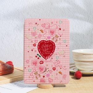 May include: A pink and white gingham patterned tablet case with the text "Pretty Girls Read Books" in a red heart. The case is decorated with hearts, bows, teddy bears, and cherries.