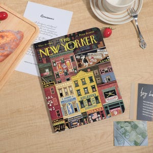 Può includere: Un taccuino con una copertina vintage della rivista The New Yorker del 18 marzo 1944. La copertina raffigura una colorata scena di strada con vari negozi e il logo della rivista. Il prezzo è di 15 centesimi.