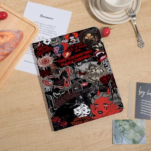 May include: A rectangular tablet case featuring a dark collage of gothic and horror-themed illustrations in black, white, and red. Graphics include a red devil, skulls, roses, and text reading Stay Spooky, I'll come back to haunt you, and That's horrifying! Please continue.