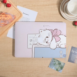 May include: A light pink laptop case featuring a cartoon cat with a pink bow. The cat is lying on a light blue surface with a document and file icons. The Japanese text "じーっー" is above the cat.