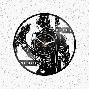 Op de afbeelding: Een ronde wandklok gemaakt van een zwarte vinylplaat met een uitgesneden silhouet van het personage Deadpool. Het ontwerp bevat de tekst DEAD en POOL, met een centrale wijzerplaat met witte wijzers en zwarte cijfers.
