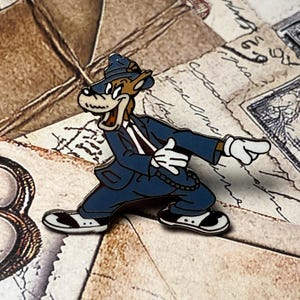 Peut inclure: Épingle en émail représentant un loup de dessin animé en costume bleu, chapeau et gants blancs, pointant du doigt. L'épingle a des détails noirs et blancs et est posée sur un fond de papier vintage.