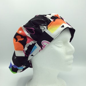 May include: A black scrub cap with a colorful geometric and heart print. The cap is made of a soft, comfortable fabric and has a tie closure.