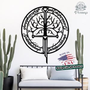 May include: Black metal wall art featuring a sword design with a tree and circular text. The artwork is displayed above a black metal bench with white and blue pillows, and two cacti. The text "MADE IN USA" is visible.