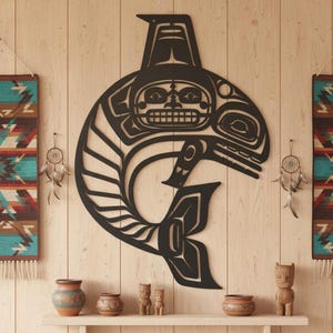 May include: A large, black, stylized orca whale wall art with intricate cut-out details. The artwork is mounted on a light wood-paneled wall, with decorative textiles and pottery adding to the rustic aesthetic. Dream catchers hang on either side of the whale.