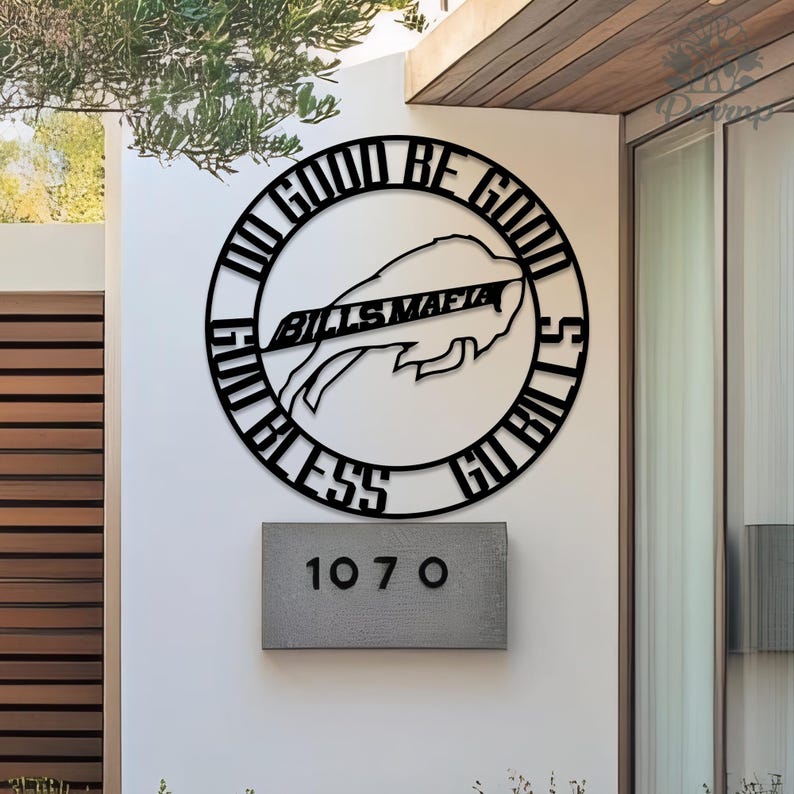 May include: Black metal wall art featuring the Buffalo Bills logo and the words "Go Bills" and "Bills Mafia" in a circular design. Below is a gray rectangular address plaque with the numbers "107 O". The art is mounted on a white wall.