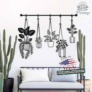May include: Black metal wall art featuring five hanging plant silhouettes. The plants are suspended from a horizontal bar. The image includes the text "MADE IN USA".