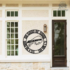May include: Black metal wall art featuring a circular design with the words "DO GOOD BE GOOD" and "GO BILLS" surrounding a buffalo logo and the words "BILLS MAFIA". The artwork is mounted on a textured wall.