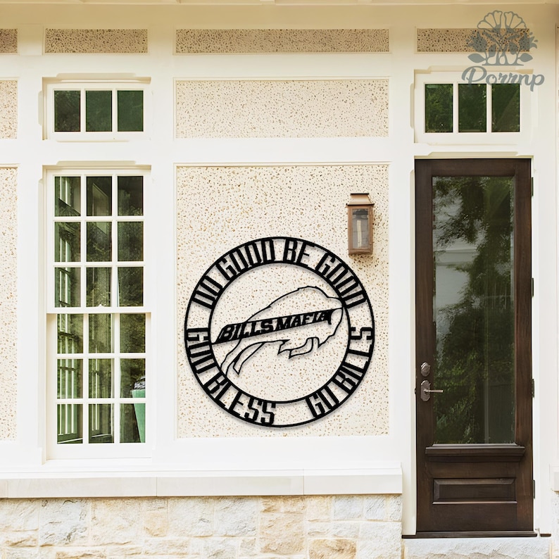 May include: Black metal wall art featuring a circular design with the words "DO GOOD BE GOOD" and "GO BILLS" surrounding a buffalo logo and the words "BILLS MAFIA". The artwork is mounted on a textured wall.