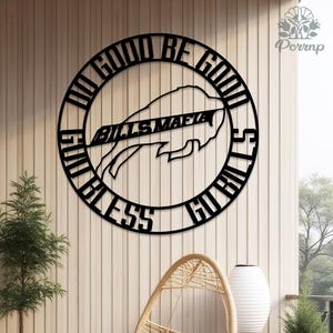 May include: A black metal wall art piece featuring the text "DO GOOD BE GOOD" and "GO BILLS" in a circular design. The words "BILLS MAFIA" are centered, with a buffalo logo. The art is mounted on a light-colored wooden wall.