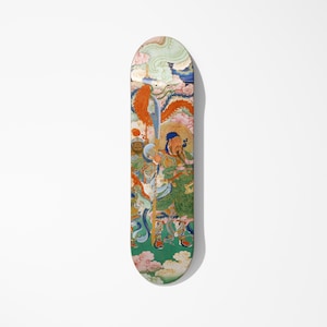 May include: A skateboard deck with a vibrant illustration of figures in traditional dress. The artwork uses green, orange, blue, and pink hues. The deck is an elongated oval shape, set against a white background. The design is detailed.