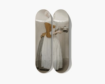May include: Two skateboard decks side-by-side, each featuring a portion of a classic painting. The artwork depicts a woman in a white dress and a yellow jacket, holding a tray with cups. The decks have a light-colored background.