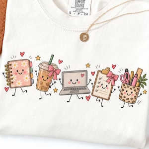 Könnte beinhalten: Ein weißes T-Shirt mit einem Grafikdruck von fünf anthropomorphen Büroartikeln: ein Notizbuch mit Gänseblümchenmuster, ein Bubble Tea mit rosa Schleife, ein Laptop, ein Klemmbrett mit rosa Schleife und ein Stiftehalter mit Leopardenmuster.