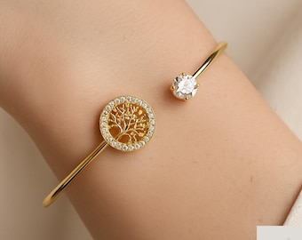 May include: Gold-tone open cuff bracelet featuring a tree of life pendant with a halo of small clear crystals. The bracelet also has a single, round, clear crystal accent. The jewelry is from Shine Jewelryyy.