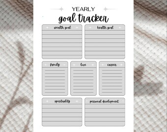 May include: A white yearly goal tracker with headings for wealth, health, family, love, career, spirituality, and personal development. The title "goal tracker" is in a handwritten style font. The tracker has lined sections for each goal.