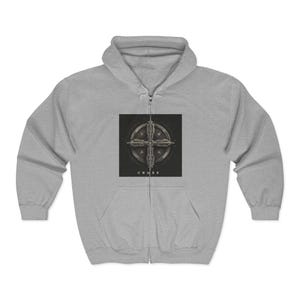 May include: A light gray zip-up hoodie featuring a detailed cross design on the front. The cross is centered on a black square, with the word "CROSS" printed below. The hoodie has a hood and a front pocket.