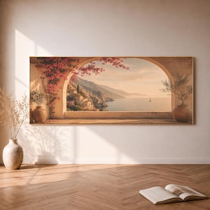 Könnte beinhalten: Ein rechteckiger Wandkunstdruck, der eine mediterrane Küstenszene durch eine gewölbte Steinöffnung zeigt. Das Bild zeigt rosafarbene Bougainvilleen, Terrakottatöpfe, ein Dorf am Hang und ein ruhiges Meer mit einem kleinen Segelboot bei Sonnenuntergang.