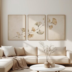May include: A triptych wall art set featuring three vertical rectangular frames with a continuous watercolour illustration of ginkgo biloba leaves in shades of beige, tan, and muted green against a textured off-white background.