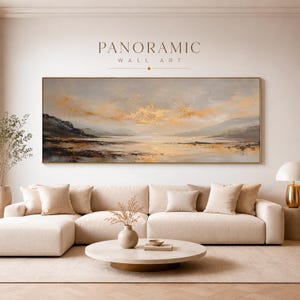 May include: A rectangular panoramic wall art piece featuring an abstract landscape painting with muted grey, beige, and metallic gold tones. The artwork depicts a horizon line with soft clouds, distant hills, and a reflective water surface.